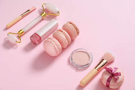 Tasty macarons with makeup cosmetics on color backgroundの写真素材