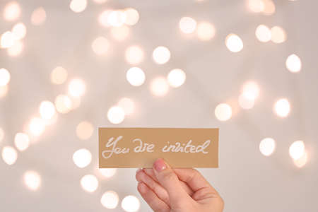 Female hand with invitation on light backgroundの写真素材