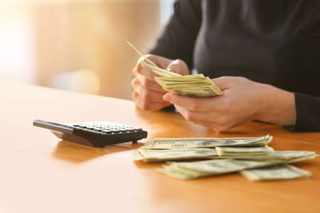 Woman counting dollar banknotes at tableの写真素材