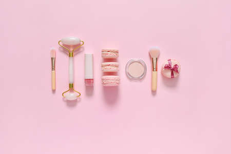 Tasty macarons with makeup cosmetics on color backgroundの写真素材