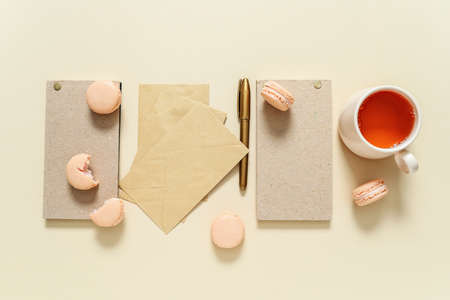 Tasty macarons with stationery and cup of tea on color backgroundの写真素材