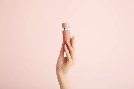 Female hand with bottle of perfume on color backgroundの写真素材