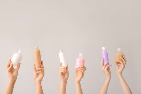 Female hands with different cosmetic products in bottles on gray backgroundの写真素材
