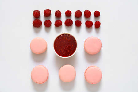 Tasty macarons with raspberry and jam on white background