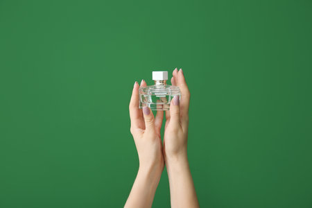 Female hands with bottle of perfume on color backgroundの写真素材