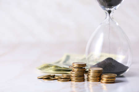 Crystal hourglass with money on light background