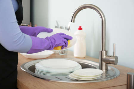 Woman washing dishes in kitchenの写真素材