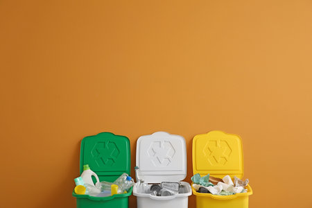 Containers with different types of garbage near color wall. Recycling concept