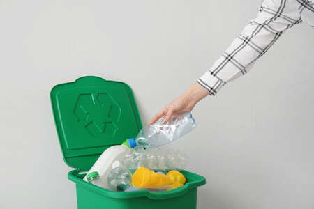 Woman throwing garbage into container. Recycling concept
