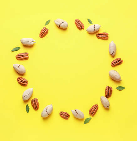 Frame made of tasty pecan nuts on color background