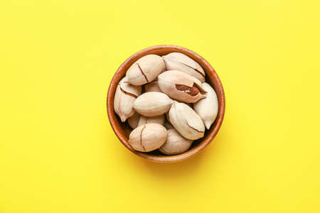 Bowl with tasty pecan nuts on color backgroundの写真素材