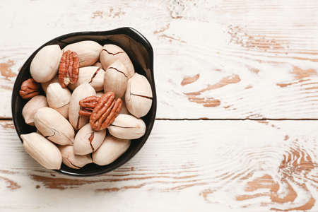 Bowl with tasty pecan nuts on wooden backgroundの写真素材