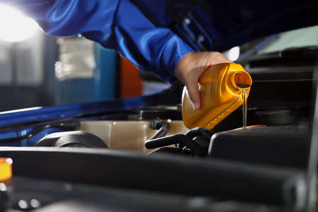 Male mechanic refilling car oil in service centerの写真素材
