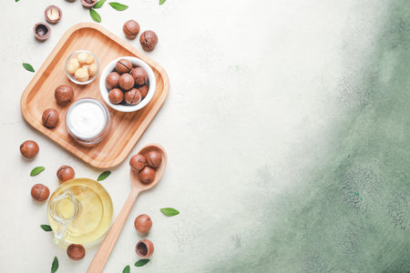 Macadamia nuts with oil and cosmetic cream on color backgroundの写真素材