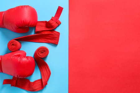 Boxing gloves and wrist bands on color background