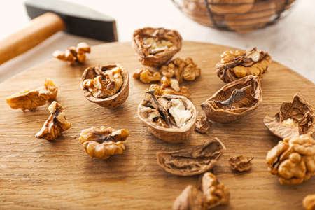 Tasty cracked walnuts on wooden board, closeup