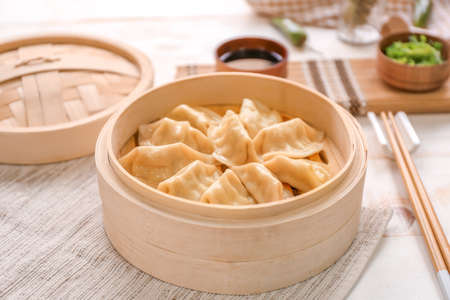 Bamboo steamer with tasty Japanese gyoza on tableの写真素材