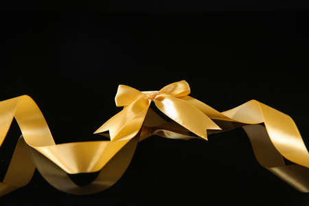 Golden ribbon with beautiful bow on dark backgroundの写真素材