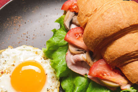 Tasty croissant sandwich with fried egg on plate, closeupの写真素材