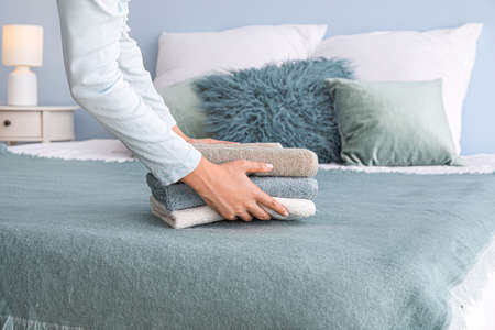 Woman putting soft towels on bed