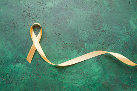 Golden ribbon on color background. Cancer awareness conceptの写真素材