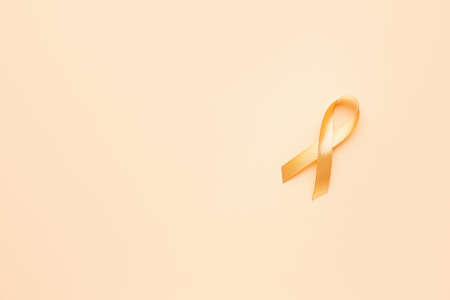 Golden ribbon on color background. Cancer awareness conceptの写真素材