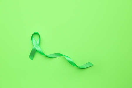 Green ribbon on color background. Cancer awareness conceptの写真素材