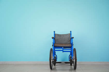 Empty wheelchair near color wallの写真素材