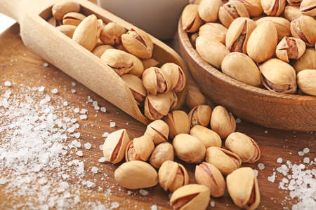 Bowl and scoop with tasty pistachio nuts on wooden background, closeupの写真素材