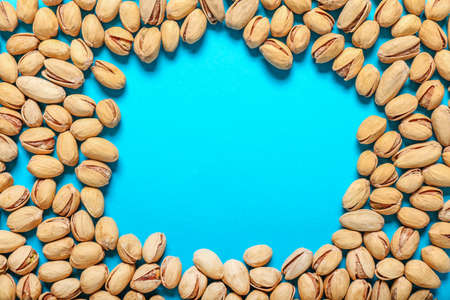 Frame made of tasty pistachio nuts on color backgroundの写真素材