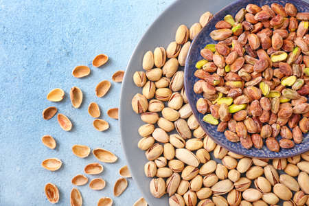 Plate with tasty pistachio nuts on tableの写真素材