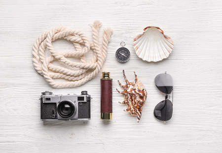 Set of travel accessories with photo camera, sunglasses and seashells on white wooden backgroundの写真素材