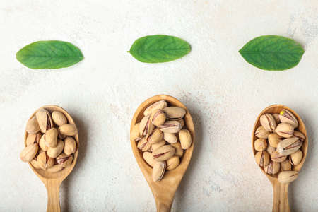 Spoons with tasty pistachio nuts on tableの写真素材