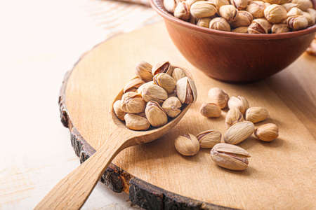 Bowl and spoon with tasty pistachio nuts on tableの写真素材
