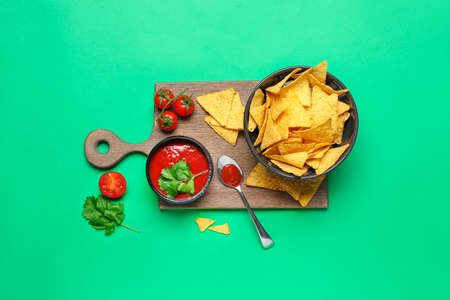 Bowl with tasty nachos and tomato sauce on color backgroundの写真素材
