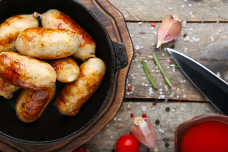 Frying pan with tasty grilled sausages on wooden tableの写真素材