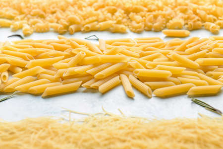 Different uncooked pasta on light table, closeup