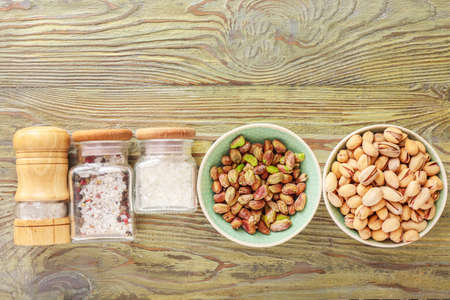 Bowls with tasty pistachio nuts and spices on tableの写真素材