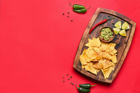 Board with tasty nachos and guacamole sauce on color backgroundの写真素材