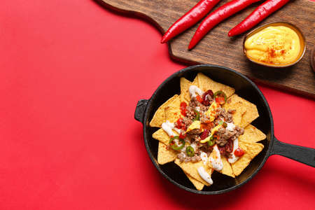 Frying pan with tasty chili con carne and nachos on color backgroundの写真素材