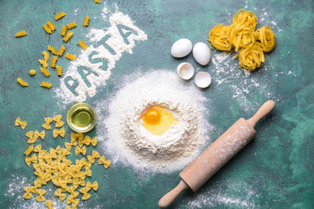 Different uncooked pasta with flour, eggs and oil on color backgroundの写真素材