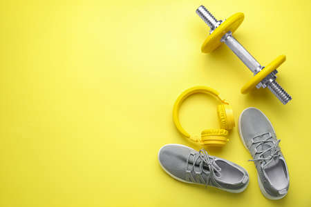 Dumbbell with shoes and headphones on color backgroundの写真素材