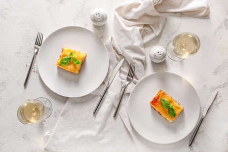 Plates with tasty baked lasagna on white background