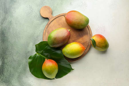 Board with mango fruit on light backgroundの写真素材