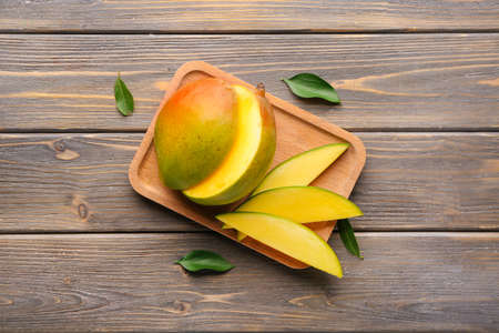 Plate with cut mango fruit on wooden backgroundの写真素材