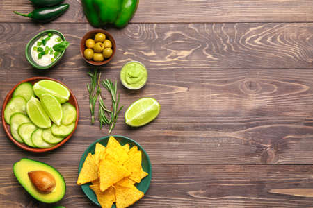 Plate with tasty nachos and products on wooden tableの写真素材