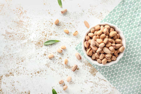 Bowl with tasty pistachio nuts on tableの写真素材