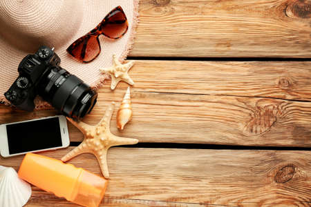 Composition with beach accessories, mobile phone and photo camera on wooden backgroundの写真素材