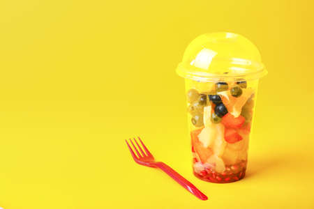 Cup with tasty fruit salad on color backgroundの写真素材