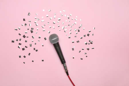 Modern microphone and confetti on color backgroundの写真素材